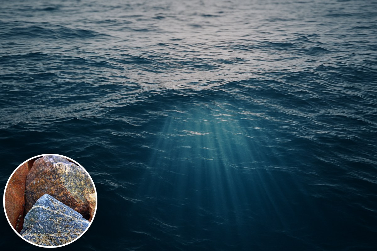 Sunlight rays piercing a deep blue ocean surface, with volcanic rocks inset.